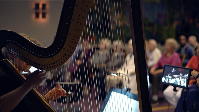 Musiker som splear harpa på ett äldreboende